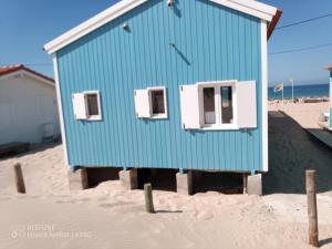 Cabana de Praia no centro de Lisboa في كاباريكا: مبنى أزرق على الشاطئ في الرمال