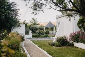 a garden with a white building and a gazebo at Klein Geluk Cottage in Nieu-Bethesda
