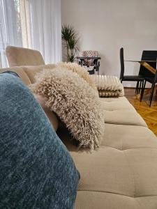a couch with pillows on it in a living room at FAMILLE Apartman in Tapolca