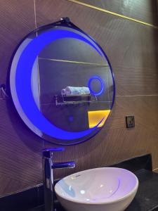 Tnmax Luxury Home Abuja في Garki: حمام مع مرآة زرقاء ومغسلة +صورتان