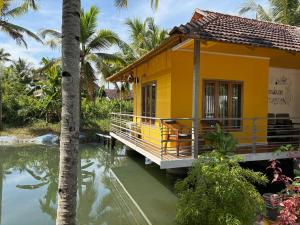 a yellow house next to a body of water at Vrindavan homestay in Munroe Island