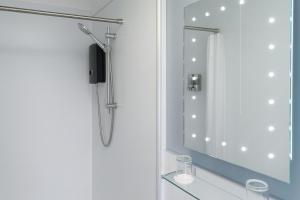 een douche in de badkamer met een spiegel bij Lochmaddy Hotel in Lochmaddy