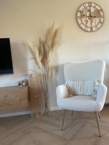 a living room with a chair and a clock on the wall at Charmante maison rénovée in Fernelmont