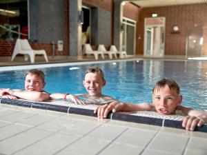 three young boys swimming in a swimming pool at Sportsby Vejen - Danhostel, huse og lejligheder in Vejen