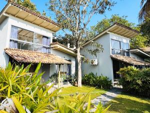 a white house with a tree in the yard at Nuraai River Chalets in Ambalangoda