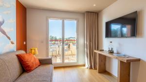 een woonkamer met een bank en een televisie bij Résidence Kaliopé in Le Lavandou