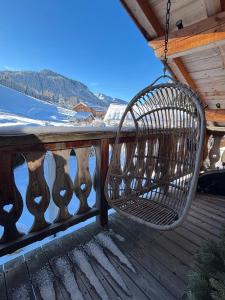 una sedia di vimini appesa alla ringhiera di un portico di Chalet Hermine a Megève