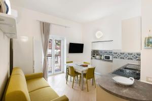 Nanninella Guest House في مينوري: غرفة معيشة مع أريكة صفراء ومطبخ