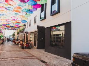 a street with people sitting in chairs under umbrellas at XPT Águeda - Alojamento Local in Águeda