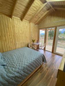 a bedroom with a bed in a room with wooden walls at Cabaña Caiquen in Villa Cerro Castillo