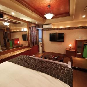 a hotel room with a bed and a flat screen tv at ホテル マリオン 鈴鹿 in Suzuka