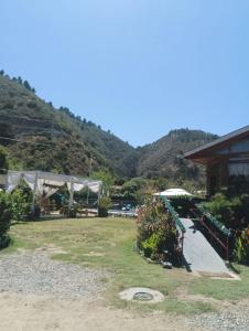 a garden with a building and mountains in the background at Cabañas Selva Negra in Valparaíso