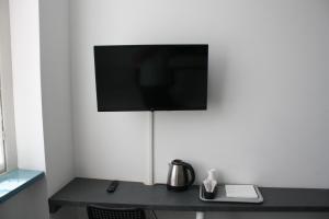 ein Schreibtisch mit einem Fernseher an einer weißen Wand in der Unterkunft BeB Gallozzo in Cesate