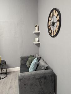 ein Wohnzimmer mit einer Couch und einer Uhr an der Wand in der Unterkunft GlowHavenStay in Manchester