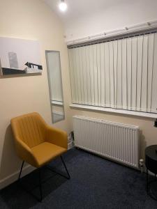 Zimmer mit gelbem Stuhl und Fenster in der Unterkunft GlowHavenStay in Manchester