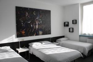 ein Zimmer mit drei Betten und einem Gemälde an der Wand in der Unterkunft BeB Gallozzo in Cesate