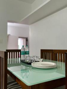 Comforts suites HVR في Sringeri: طاولة زجاجية عليها طبق وزجاجات ماء