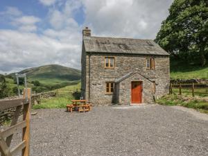 an old stone house with a red door and a table at Howgill Head in Kendal