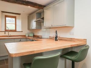 a kitchen with a wooden counter and two green chairs at Howgill Head in Kendal +33 photos