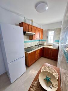 Una cocina con un refrigerador blanco y una mesa. en Terraza al mar, en Candelaria