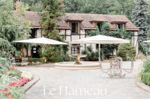 a patio with two umbrellas and chairs in front of a house at Domaine de la Butte Ronde in La Boissière-École