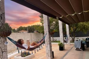 a woman laying in a hammock reading a book at Villa Jazmín - Piscina - BBQ - Jardín - Chill out in Masía Aldamar +42 photos