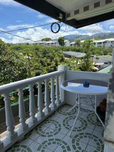 Un balcón con barandilla blanca y una mesa. en Dortoir 1, en Faaa