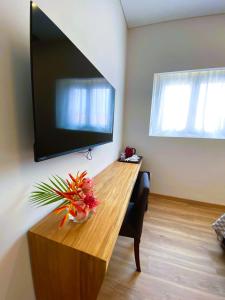 a living room with a wooden table with a tv on the wall at GUMBELA - Hotel in São Tomé