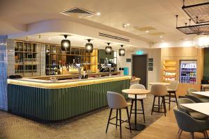 un restaurante con un bar verde con mesas y sillas en London Luton Vale Hotel, en Luton