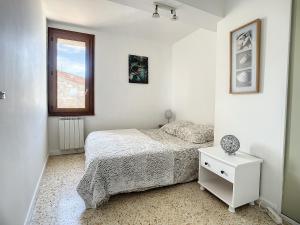 Una habitación blanca con una cama y una ventana en Quai n16 - Lieu atypique pour un séjour au calme, en Aramon