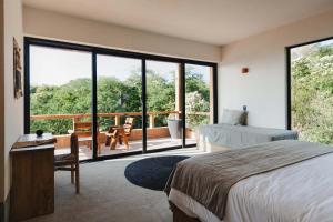 Un dormitorio con una cama y una gran ventana de cristal. en Casa Yute by Ahau Collection, en San Agustinillo