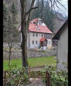 una casa blanca con techo rojo y un árbol en Sauna Chata BedRich, en Bedřichov