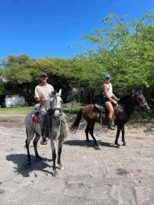dos personas montando a caballo en un camino de tierra en Finca Buena Vida, en Popoyo