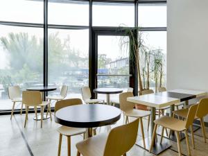 a restaurant with tables and chairs and a large window at B&B HOTEL Padova in Padova