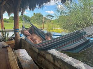 un hombre y un niño acostados en una hamaca en Finca Buena Vida, en Popoyo