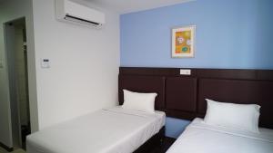 two beds in a room with a blue wall at Hotel Cascada in Kota Tinggi