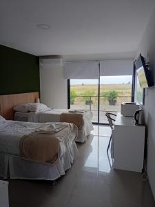 a hotel room with three beds and a large window at PLC Hotel Centenario in Paso de los Toros