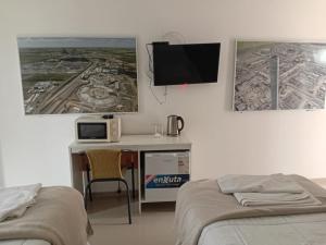 a bedroom with two beds and a desk with a tv at PLC Hotel Centenario in Paso de los Toros