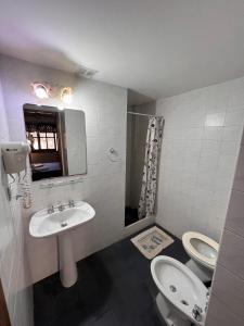 Un baño con dos inodoros, un lavabo y una ducha. en Hotel Ibiza, en Villa Gesell