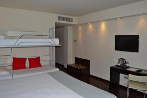 a bedroom with a bunk bed and a desk with a television at Hotel Ceuta Puerta de Africa in Ceuta