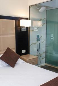 a bedroom with a bed and a glass shower at Hotel Liro - Adults Only in Vlorë