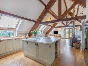 an open kitchen with white cabinets and wooden beams at Bedw Barn in Newtown