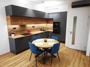 a kitchen with a wooden table and blue chairs at Diamond Apartment Brno in Brno
