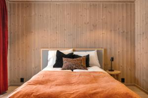 a bed with an orange blanket and pillows on it at Trysil hytteomrade 2041 by Vacation Trysil in Hovi +15 photos
