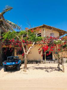 a blue truck parked in front of a house with flowers at Casa Liria Gael - Kite Is Surf School in Jericoacoara