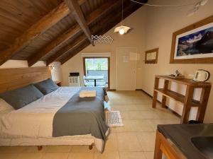 a bedroom with a large bed and a kitchen at Campo Base Aparts in El Chalten