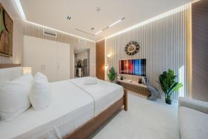 a bedroom with a large white bed and a television at Amazing Studio in Areej Aljada in Sharjah