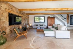 a living room with white furniture and a stone wall at Villa Neuve Corse sud avec vue mer et piscine chauffée in Pianottoli-Caldarello