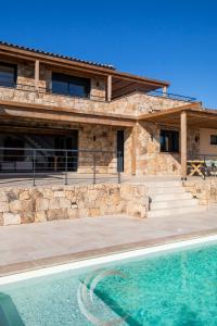 a stone house with a swimming pool in front of it at Villa Neuve Corse sud avec vue mer et piscine chauffée in Pianottoli-Caldarello