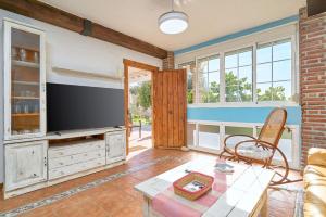 ein Wohnzimmer mit Flachbildfernseher und Tisch in der Unterkunft Villa La Canarita in La Cala del Moral